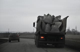 A truck carries a pile of concrete obstacles, known as dragon’s teeth, on a road among fields in the Dnipropetrovsk region